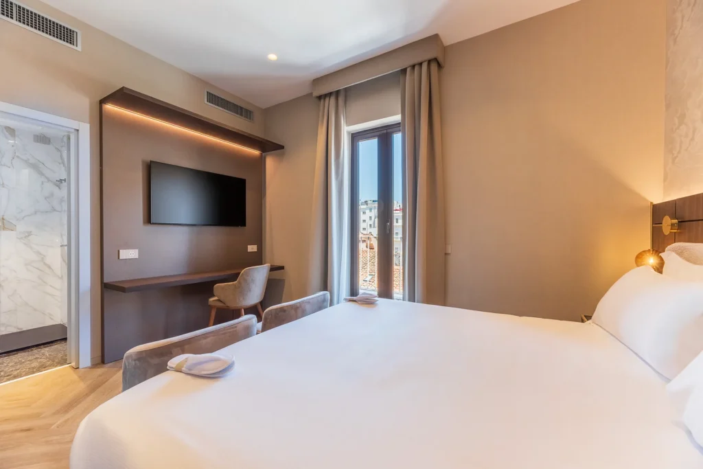 Camera rinnovata dal design moderno dell’Hotel Raffaello con letto matrimoniale, scrivania, TV a parete e accesso al bagno
